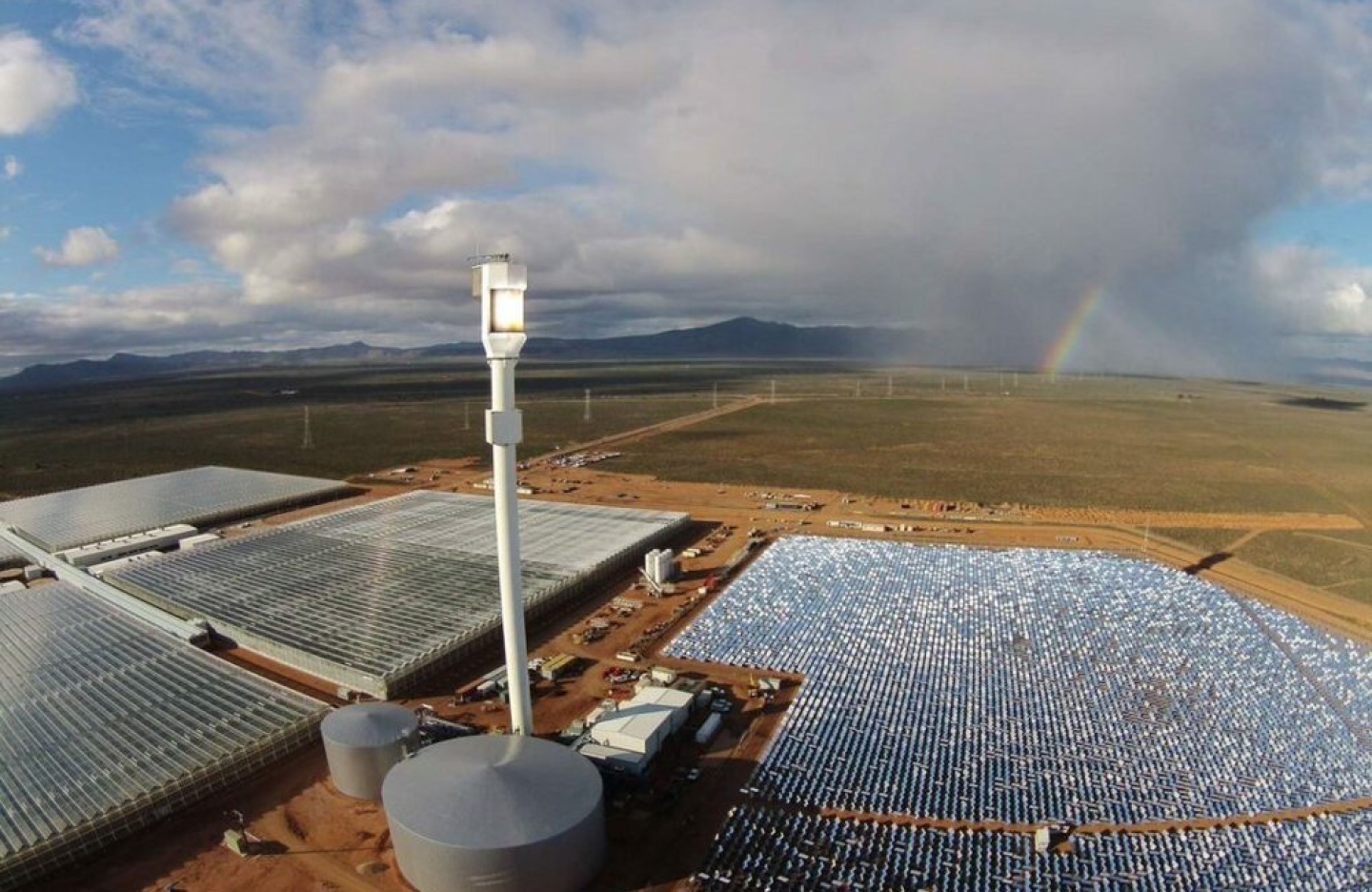 solar panels, silos, and greenhouses line the surface of an outback scenery in Australia