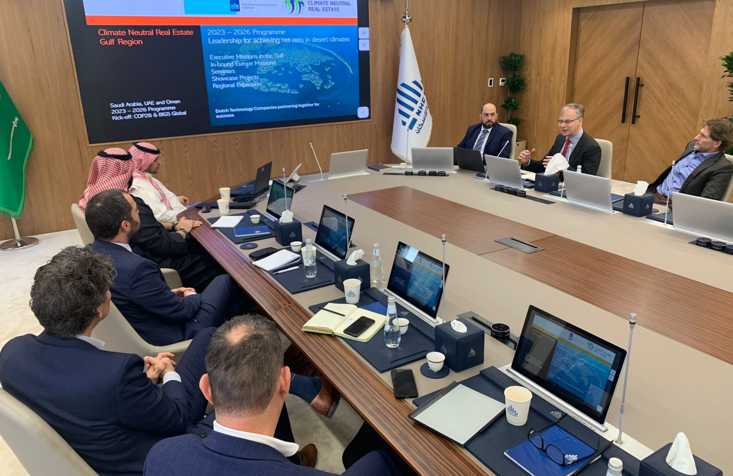 cluster partners sit at a conference table and look at a screen