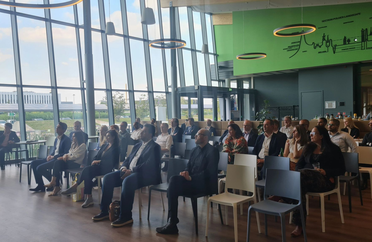 an image of a crowded conference presentation where people sit at chairs facing a stage and speaker