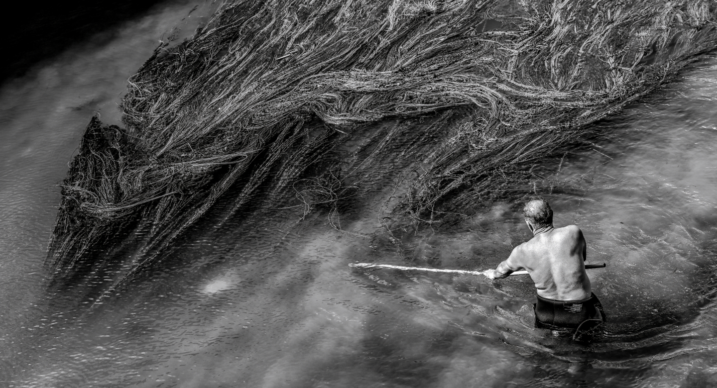 Man cleaning the water weeds and garbage the Crn Drim River in North Macedonia by Tomislav Georgiev