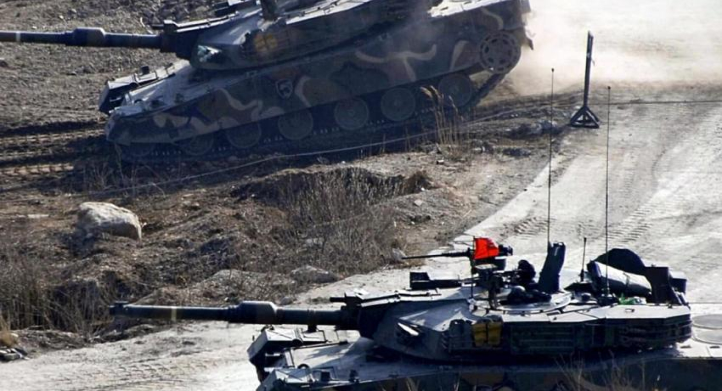 Two tanks with red flags on the top on rocky terrain