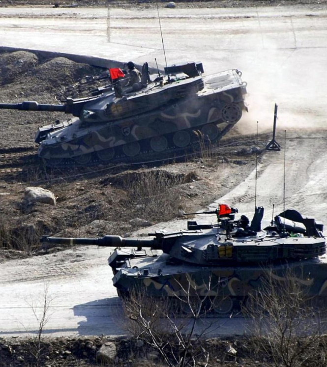 Two tanks with red flags on the top on rocky terrain
