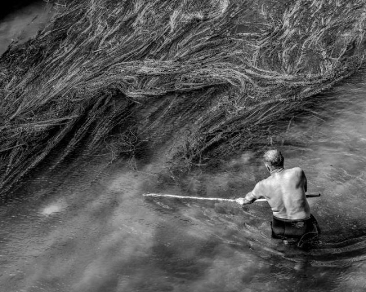 Man cleaning the water weeds and garbage the Crn Drim River in North Macedonia by Tomislav Georgiev
