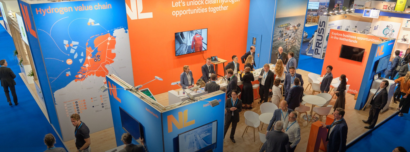 A NL booth at a trade mission pictured from above. People are discussing and doing business with each other.