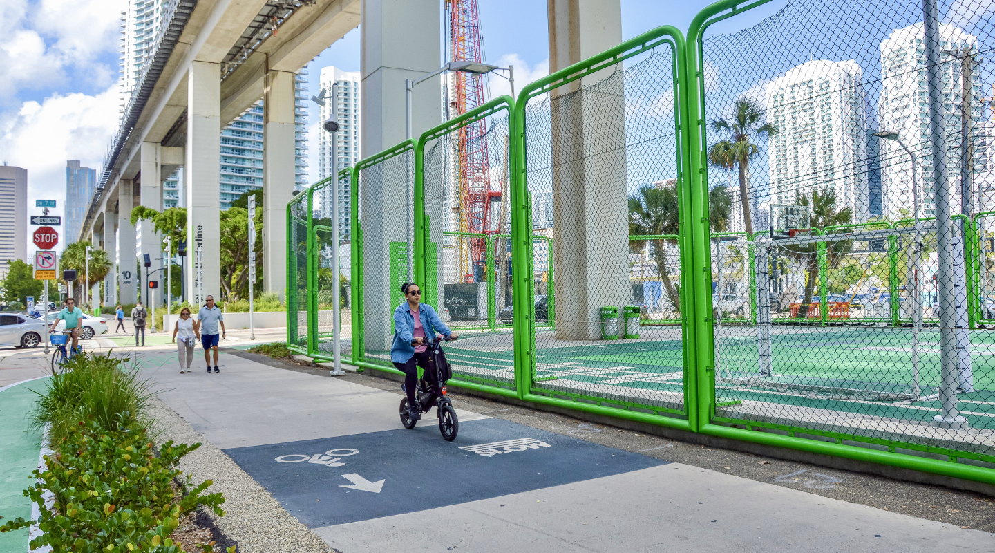 A woman cycles past sports complexes next to the Underline in Miami 