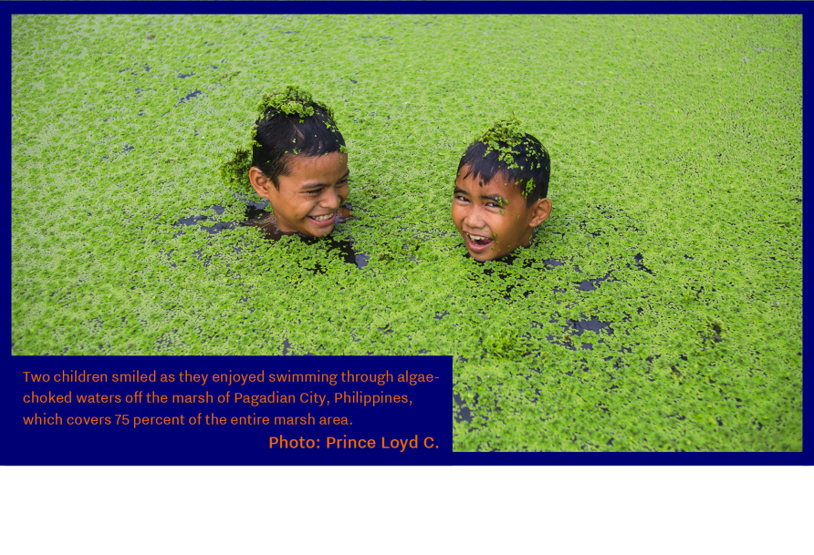 Two children smiled as they enjoyed swimming through algae-choked waters off the marsh of Pagadian City, Philippines, which covers 75 percent of the entire marsh area. Photo: Prince Loyd C. Besorio