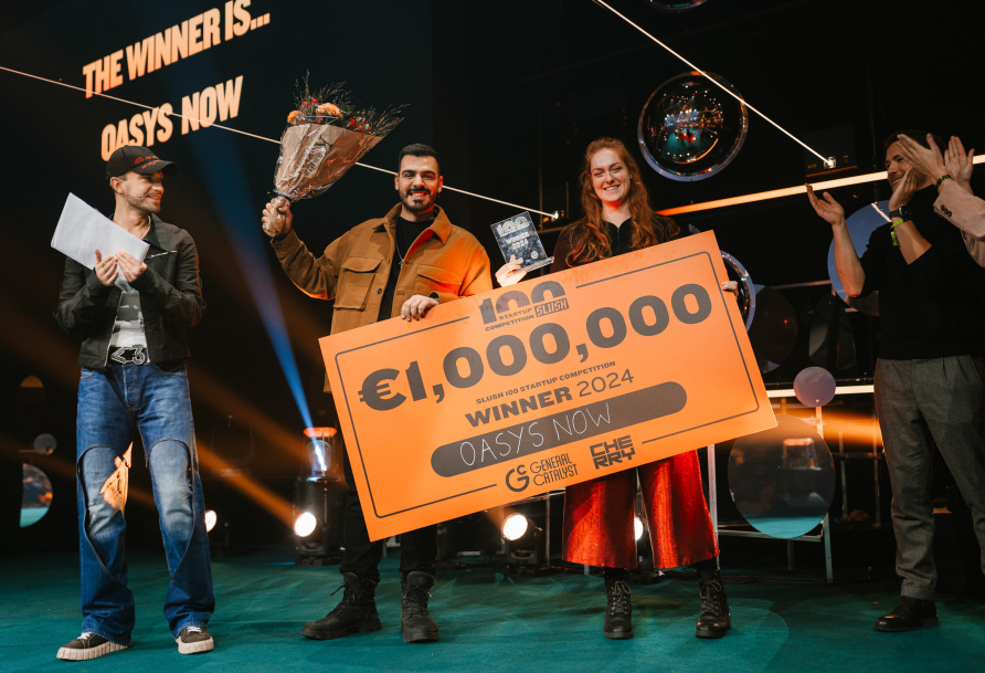 Startup duo from OASYS NOW stands on the podium celebrating their Slush 100 competition win with a check for 1000000 euro.