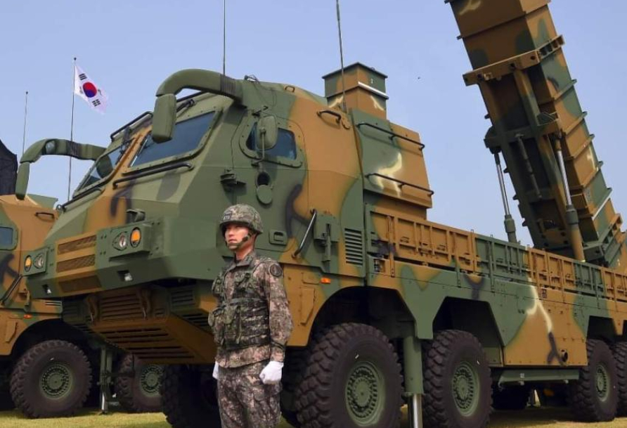 man stands next to armored vehicle with camo and turret gun