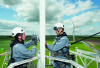 Two men in hard hats perform maintenance on a wind turbine